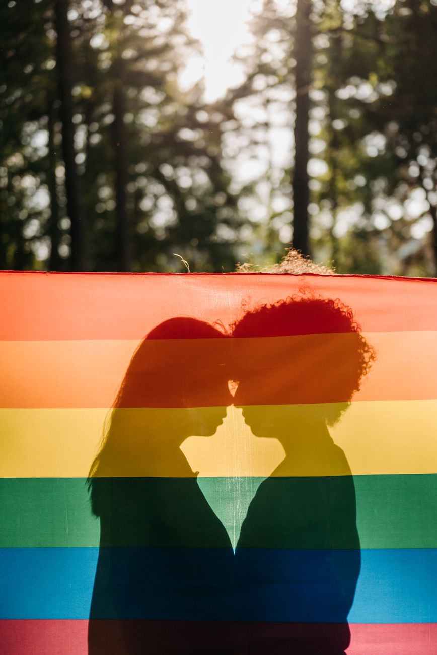 silhouette of a couple behind a rainbow flag
